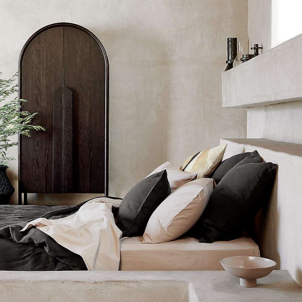 Crate & Barrel Annie 38" Charcoal Brown Storage Cabinet placed beside a bed in a warm, contemporary bedroom