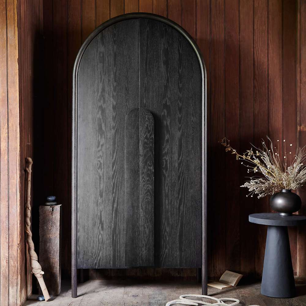 Crate & Barrel Annie 38" Charcoal Brown Storage Cabinet styled against a wood-paneled wall with modern decorative accents