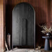 Crate & Barrel Annie 38" Charcoal Brown Storage Cabinet styled against a wood-paneled wall with modern decorative accents