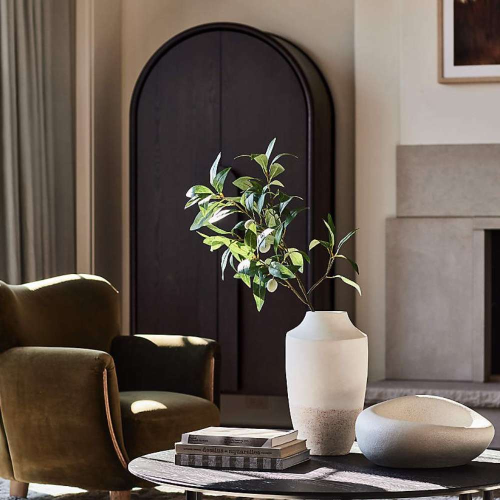 Crate & Barrel Annie 38" Charcoal Brown Storage Cabinet styled in a living room behind a coffee table with decorative vases and greenery
