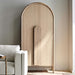 Crate & Barrel Annie 38" Natural Storage Cabinet placed beside a sofa, highlighting its tall arched design and natural wood finish