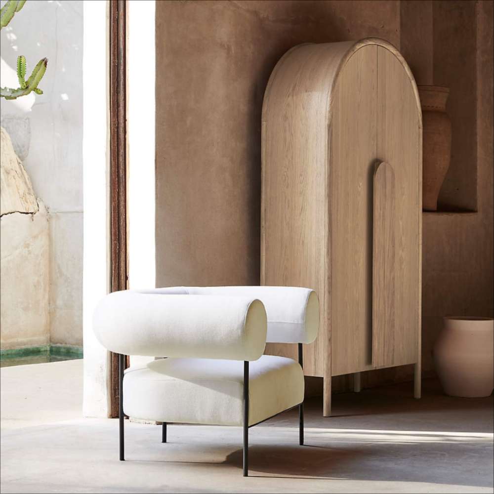 Crate & Barrel Annie 38" Natural Storage Cabinet styled beside a modern accent chair in a warm, contemporary space