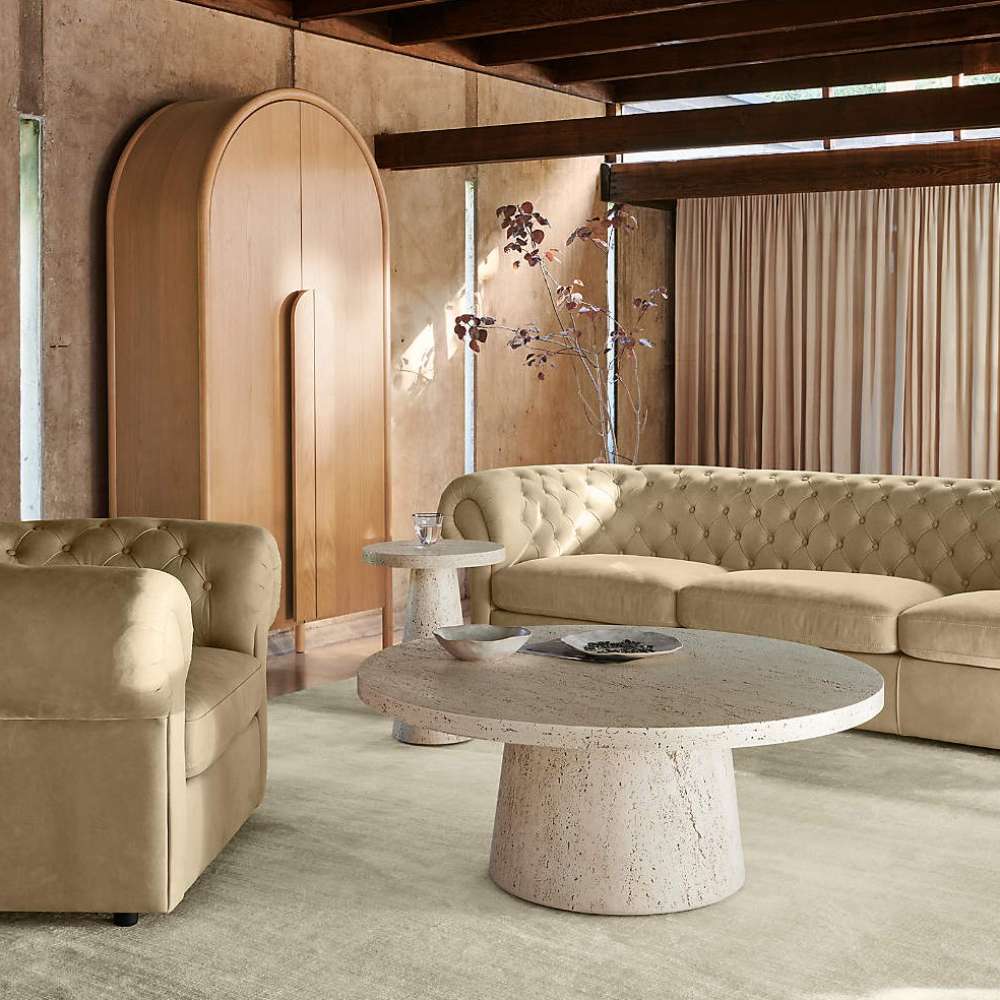 Crate & Barrel Annie 38" Natural Storage Cabinet styled in a living room with curved seating and a round stone coffee table