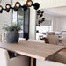 Crate & Barrel Casement 32" Black Storage Cabinet stands against a paneled wall beside a dining area, displaying its tall glass doors and slim black metal frame
