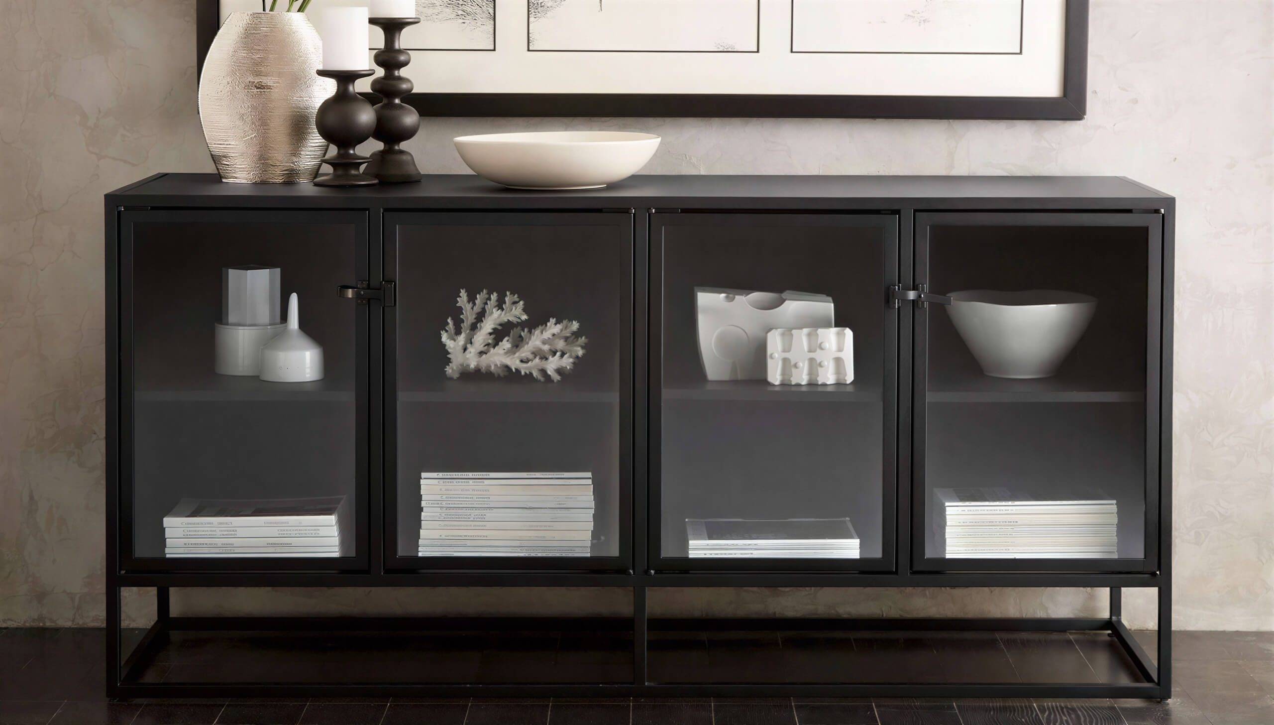 Crate & Barrel Casement 66" Black Credenza displays decorative bowls, books, and accents on two shelves behind smoked glass doors