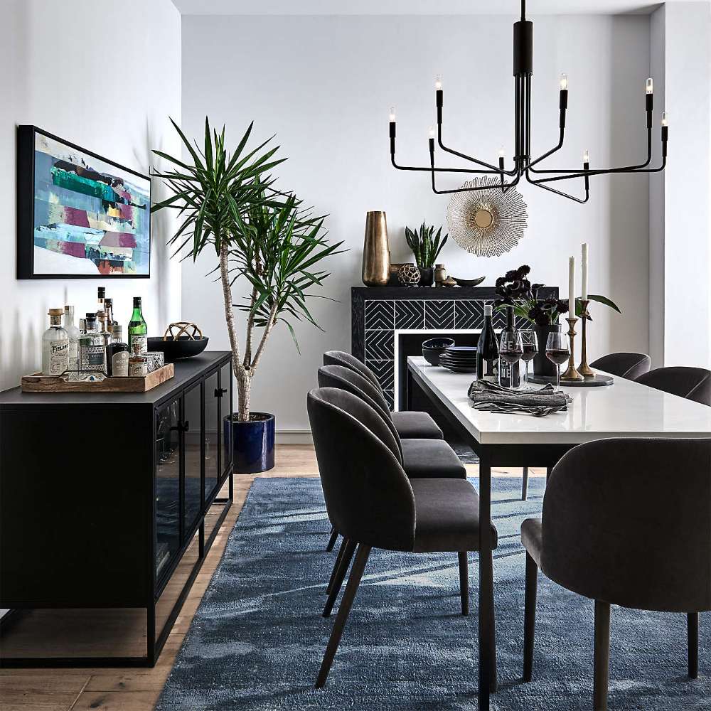 Crate & Barrel Casement 66" Black Credenza serves as a stylish dining room sideboard, holding barware and decorative accents beside a dining table