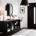 Crate & Barrel Casement 66" Black Credenza sits beneath a wall mirror in a modern entryway, displaying books, décor, and storage behind glass doors