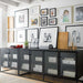 Crate & Barrel Casement 66" Black Credenza stands below a gallery wall, organizing books, storage boxes, and framed photos behind four glass doors