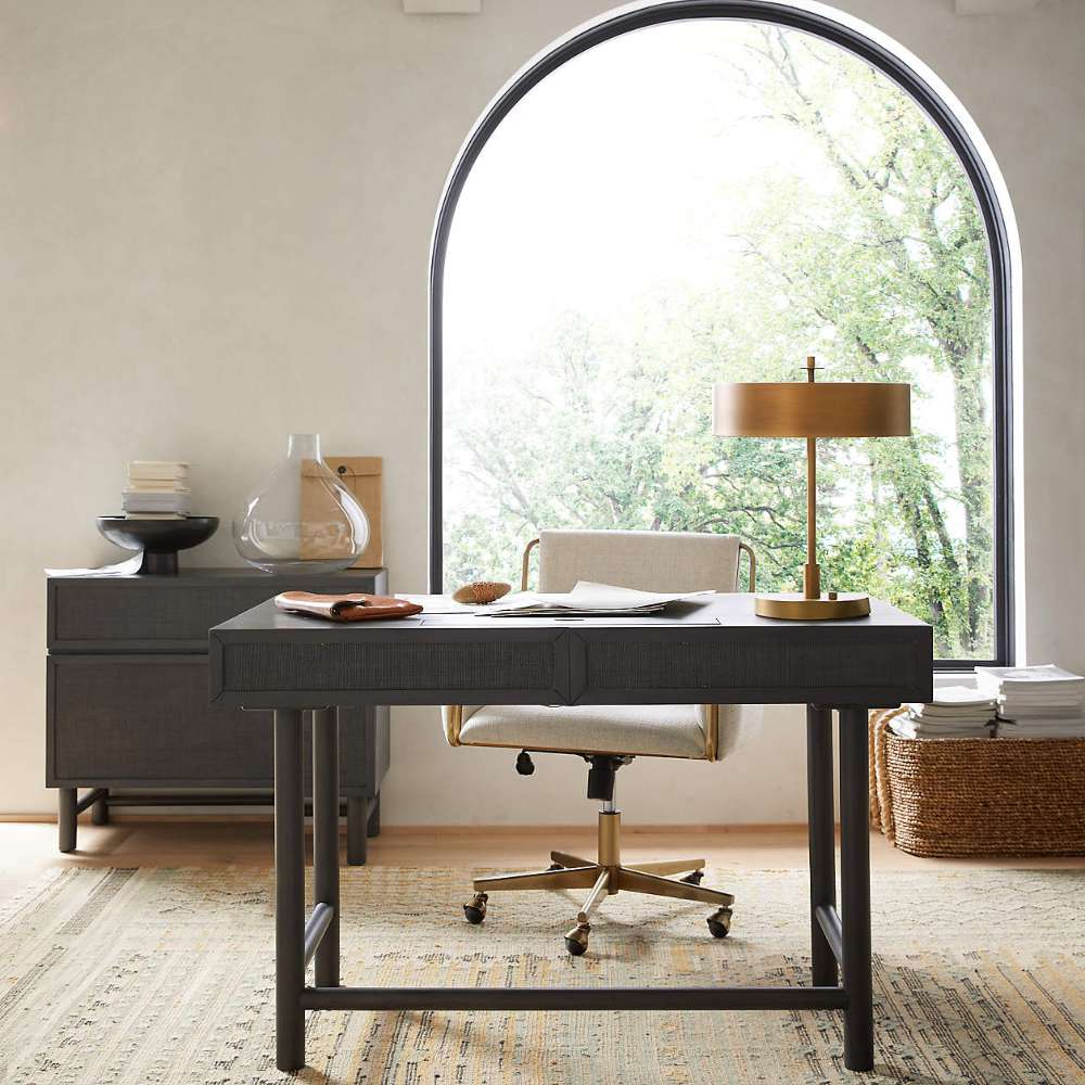 Crate & Barrel Caterina Natural Upholstered Office Chair with Brass Base styled at a dark wood desk in a bright home office with a large arched window