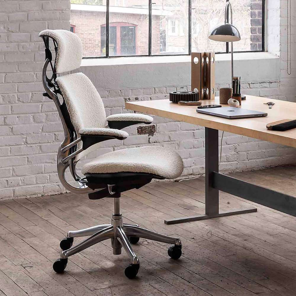 Crate & Barrel Humanscale® Freedom Headrest White Boucle Office Chair placed beside a modern desk in a bright home office with large windows and wood flooring