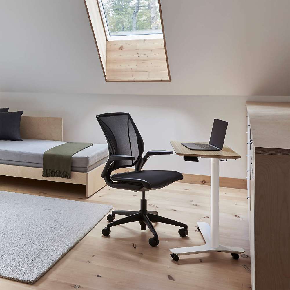 Crate & Barrel Humanscale® World LM Seat Task Office Chair is paired with a compact standing desk in a bright loft bedroom with a skylight