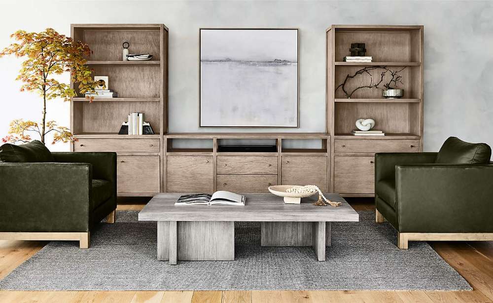 Crate & Barrel Keane 40" Natural Storage Bookcase, Set of 2 styled with books, decor, and storage cabinets in a contemporary seating area