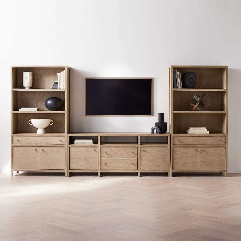 Crate & Barrel Keane 40" Natural Storage Bookcase, Set of 2 with matching media cabinets and a wall-mounted TV in a modern living room