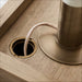 Crate & Barrel Keane 48" Weathered Natural Wood Desk with Outlets close-up of the desktop cable management opening with a cord routed through