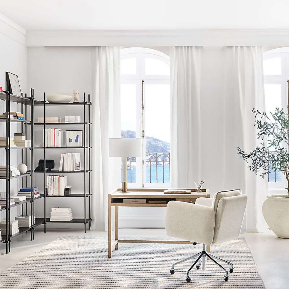 Crate & Barrel Keane 48" Weathered Natural Wood Desk with Outlets styled in a bright home office with a rolling chair and bookshelves