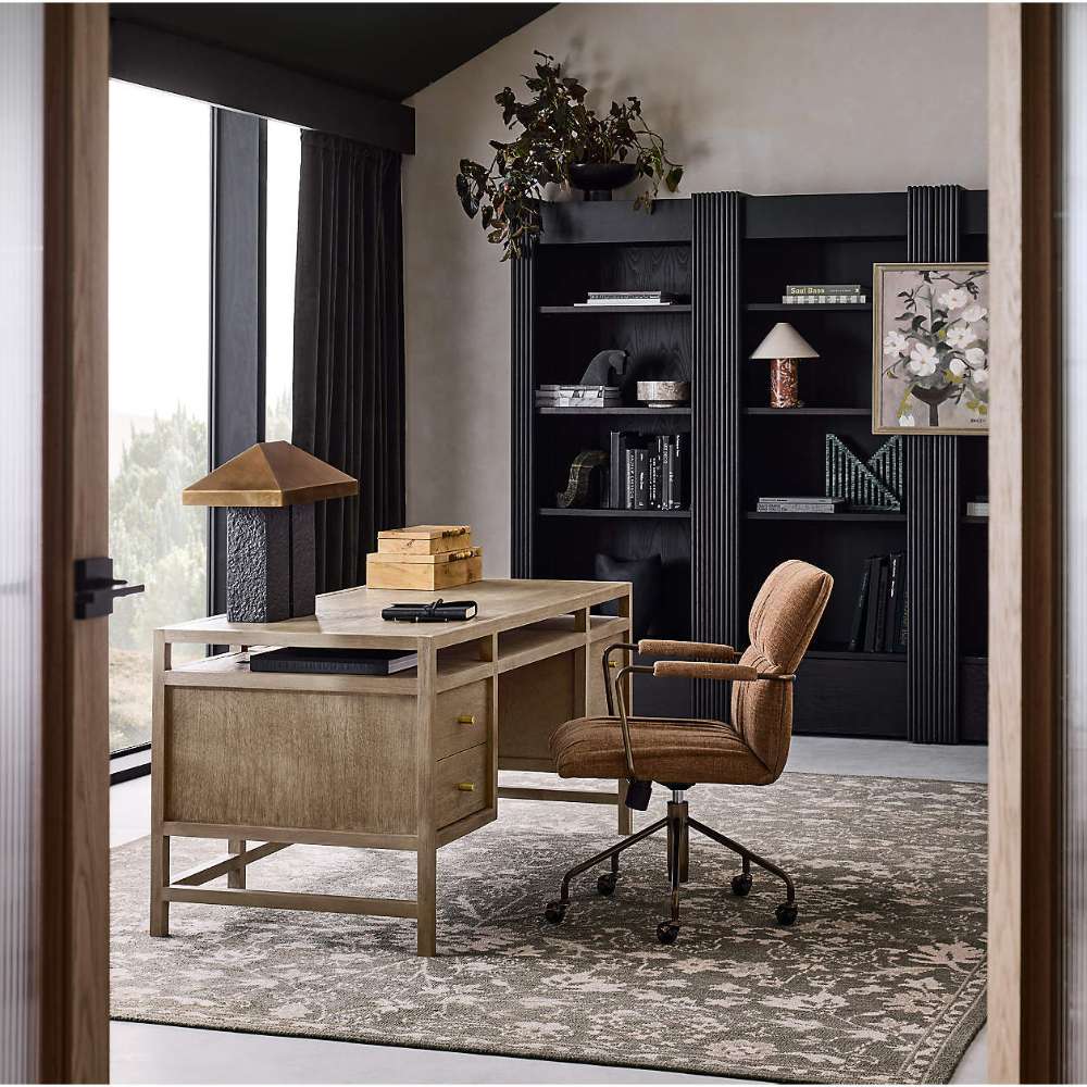 Crate & Barrel Keane 65" Weathered Natural Wood Desk with Outlets styled in a modern home office with a rolling chair and dark bookcases
