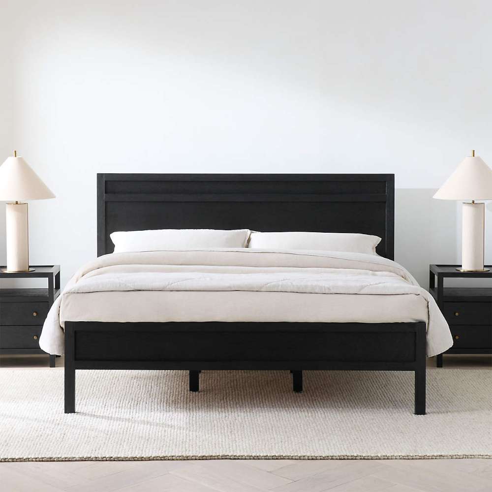 Crate & Barrel Keane Black Solid Wood King Bed styled in a modern bedroom with white bedding, matching black nightstands, and white table lamps