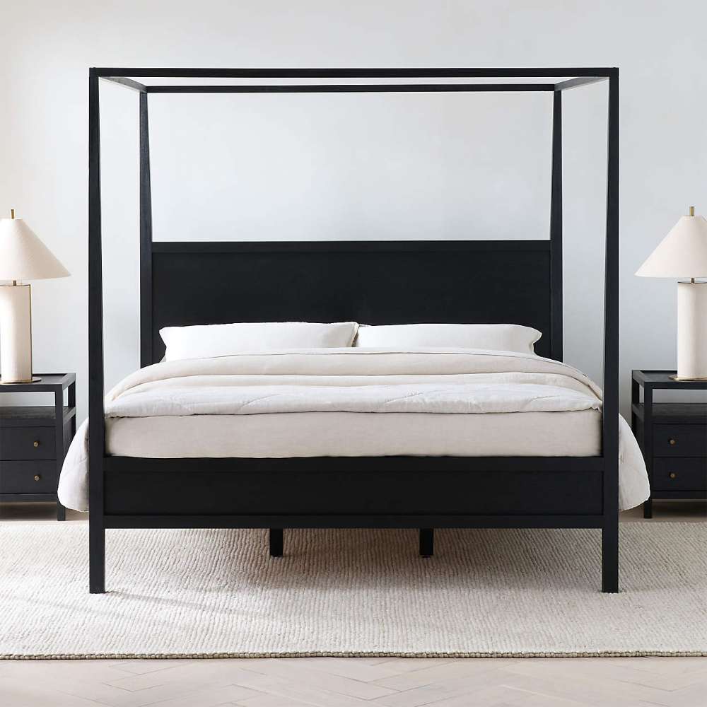Crate & Barrel Keane Black Solid Wood King Canopy Bed is shown from the front with a sleek black canopy frame, solid wood headboard, and matching nightstands
