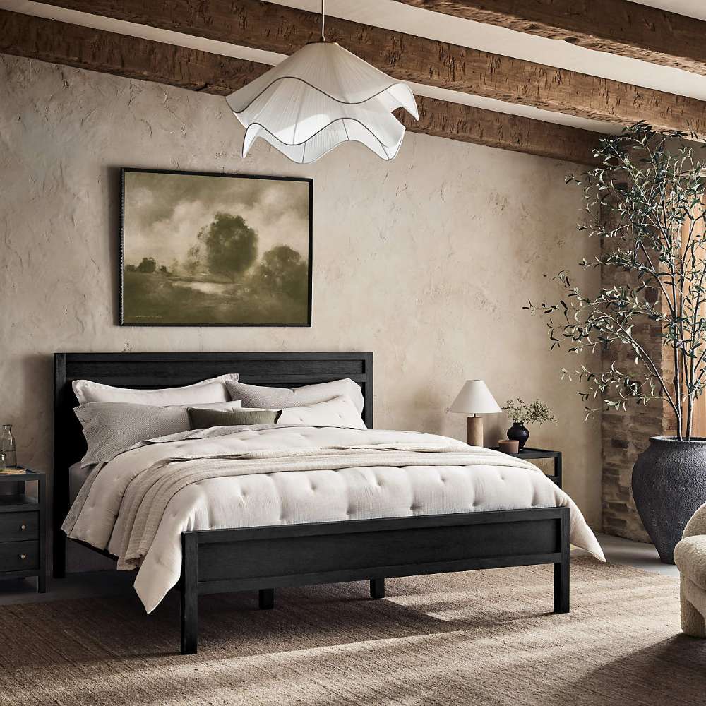 Crate & Barrel Keane Black Solid Wood Queen Bed is styled in a cozy bedroom with layered white bedding, black nightstands, and rustic decor
