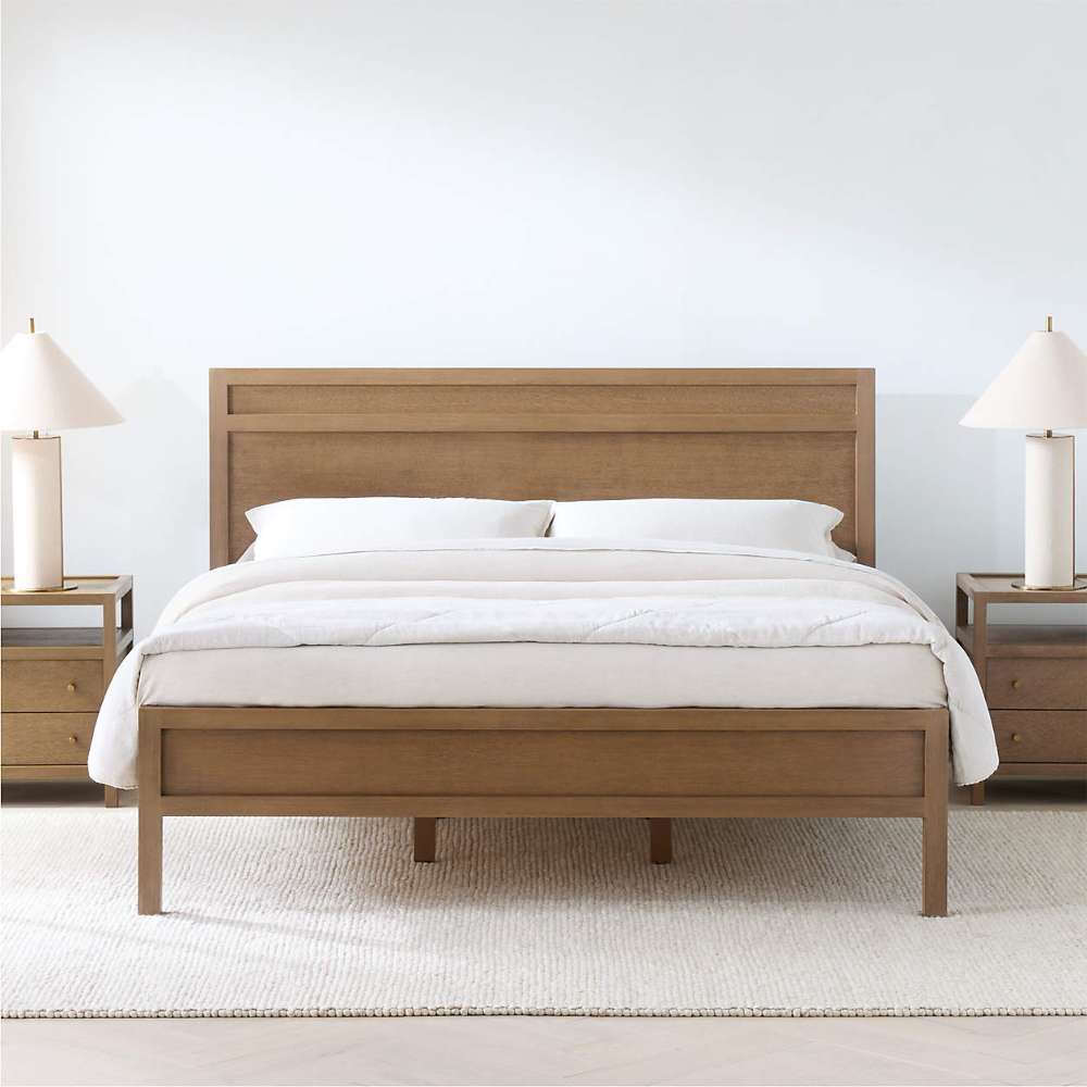 Crate & Barrel Keane Solid Driftwood King Bed centered in a bright bedroom with white bedding, matching nightstands, and table lamps