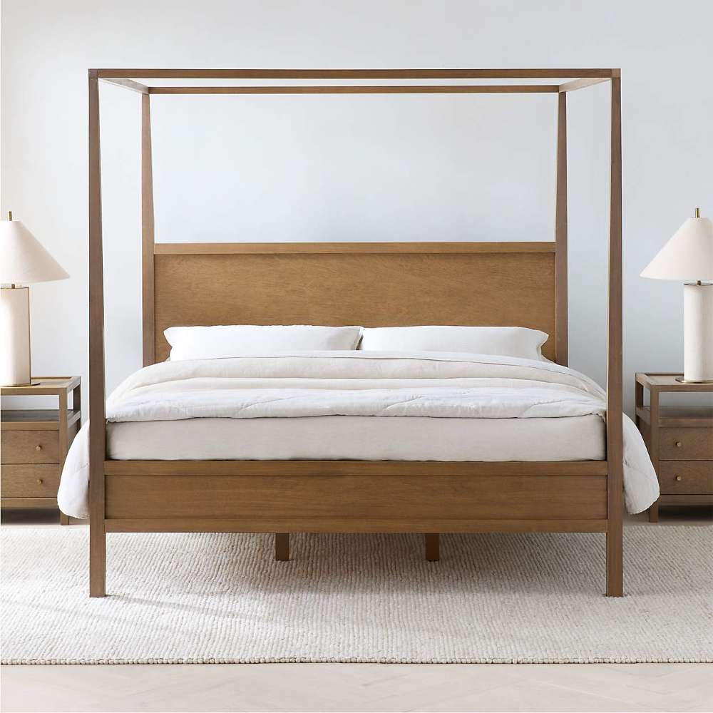 Crate & Barrel Keane Solid Driftwood King Canopy Bed is shown from the front with a slim wood canopy frame, solid headboard, and matching nightstands