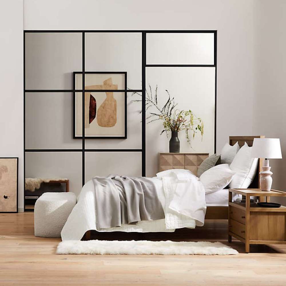 Crate & Barrel Keane Solid Driftwood Queen Bed is styled in a modern bedroom with layered bedding, wood furniture, and minimalist decor