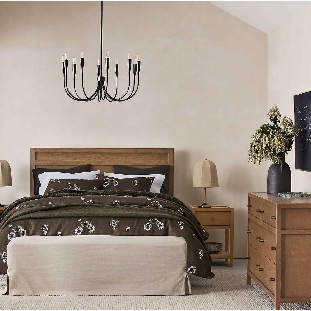 Crate & Barrel Keane Solid Driftwood Queen Bed is styled in an elegant bedroom with dark floral bedding, a bench, and matching wood furniture