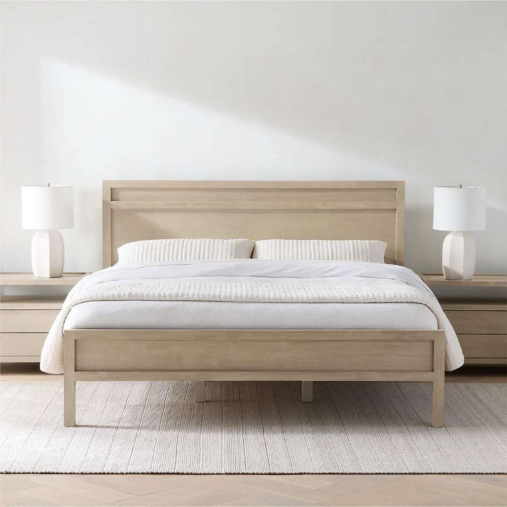 Crate & Barrel Keane Weathered Natural Solid Wood King Bed styled in a bright bedroom with white bedding, matching nightstands, and white table lamps