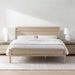 Crate & Barrel Keane Weathered Natural Solid Wood King Bed styled in a bright bedroom with white bedding, matching nightstands, and white table lamps