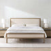 Crate & Barrel Keane Weathered Natural Wood Upholstered Queen Bed is styled in a bright bedroom with matching nightstands, white bedding, and table lamps