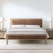 Crate & Barrel Keane Weathered Natural Wood and Leather Queen Bed is shown in a bright bedroom with matching nightstands, white bedding, and warm leather panels