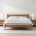 Crate & Barrel Linea Natural Teak Wood Bed centered in a simple bedroom with white bedding, matching nightstands, lamps, and a neutral rug