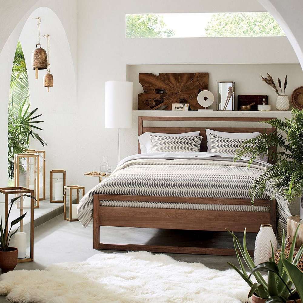 Crate & Barrel Linea Natural Teak Wood Bed in a bright bedroom with white bedding, plants, lanterns, and warm wood decor