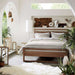 Crate & Barrel Linea Natural Teak Wood Bed in a bright bedroom with white bedding, plants, lanterns, and warm wood decor