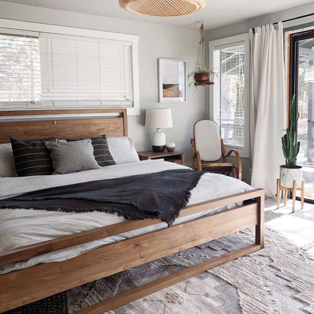 Crate & Barrel Linea Natural Teak Wood Bed styled with neutral bedding, dark accent pillows, a black throw blanket, and natural room decor