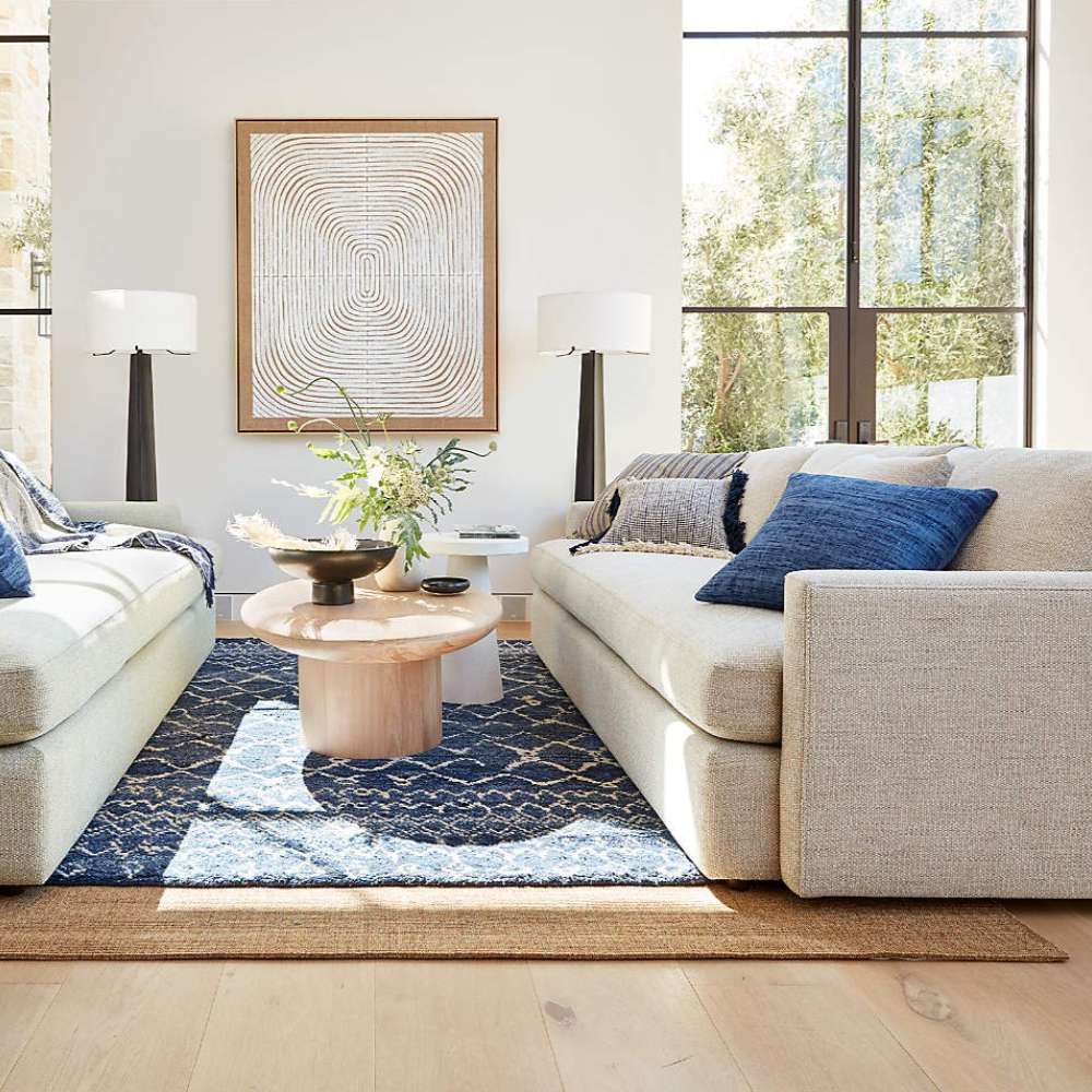 Crate & Barrel Lounge Sofa anchors a bright living room with blue accent pillows, a round coffee table, and large windows