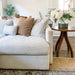 Crate & Barrel Lounge Sofa displayed in a bright living room with layered accent pillows beside a round wood side table with fresh flowers