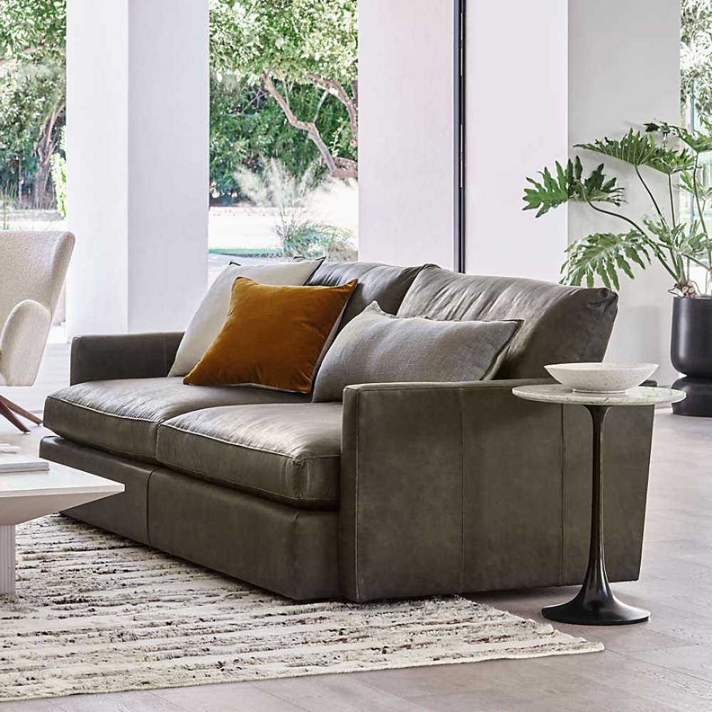 Crate & Barrel Lounge Sofa in a bright modern living room with gray leather upholstery, accent pillows, and a round side table