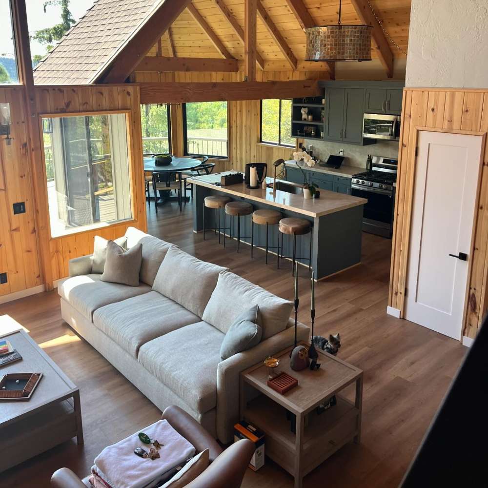 Crate & Barrel Lounge Sofa placed in a spacious wood cabin living area facing an open kitchen with large windows and vaulted ceilings