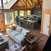 Crate & Barrel Lounge Sofa placed in a spacious wood cabin living area facing an open kitchen with large windows and vaulted ceilings