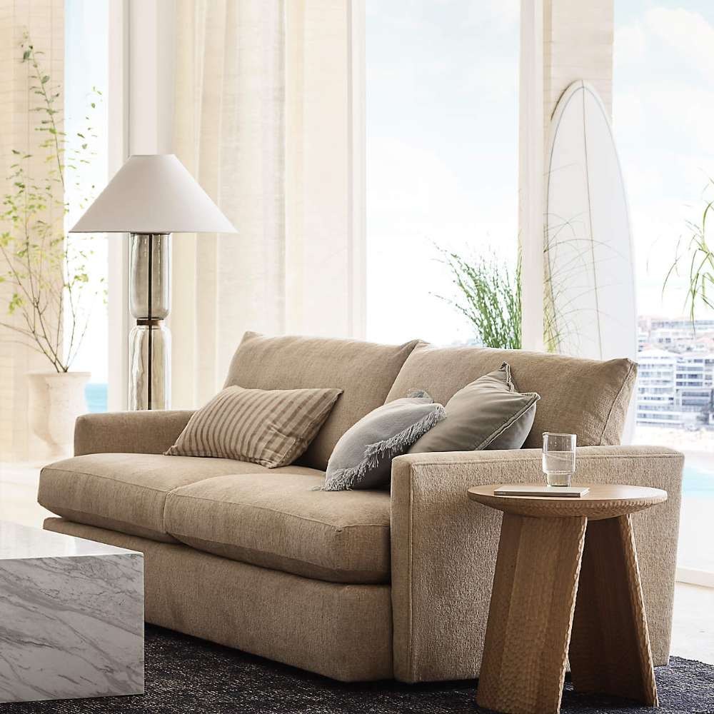 Crate & Barrel Lounge Sofa styled with striped and neutral pillows beside a round wood side table in a bright living room