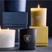 Crate & Barrel Monochrome Scented Candle collection displayed in black, white, and gold vessels with NFL team logos and glowing flames
