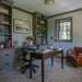 Crate & Barrel Morris 48" Chocolate Brown Writing Desk in a home office with built-in shelves, a chair, lamp, rug, and leather armchair