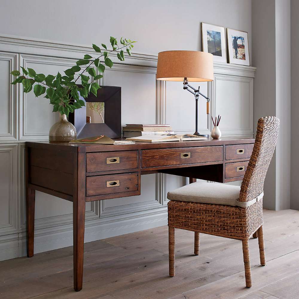 Crate & Barrel Morris 60" Chocolate Brown Writing Desk styled with a woven chair, table lamp, books, and decorative accessories