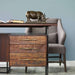 Crate & Barrel Sedgwick Solid Acacia Wood Desk with Storage features three wood drawers with brass handles beneath the desktop and a decorative rhino sculpture on top