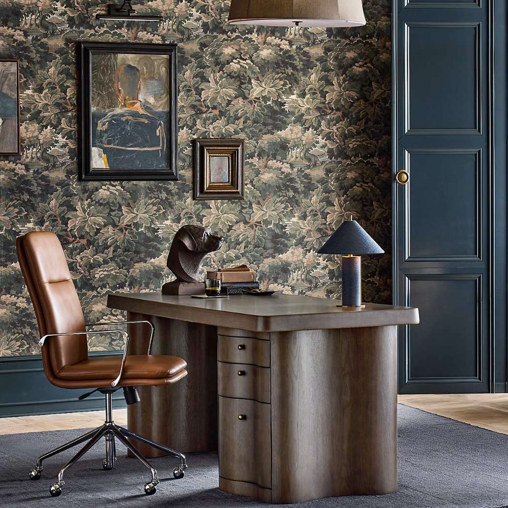 Crate & Barrel Smythe Camel Faux Leather Office Chair placed beside a modern executive desk in a stylish home office with dark walls and patterned wallpaper