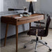 Crate & Barrel Tate 48" Walnut Desk with Outlet styled in a living room workspace beside a sofa, with decorative items displayed on its desktop