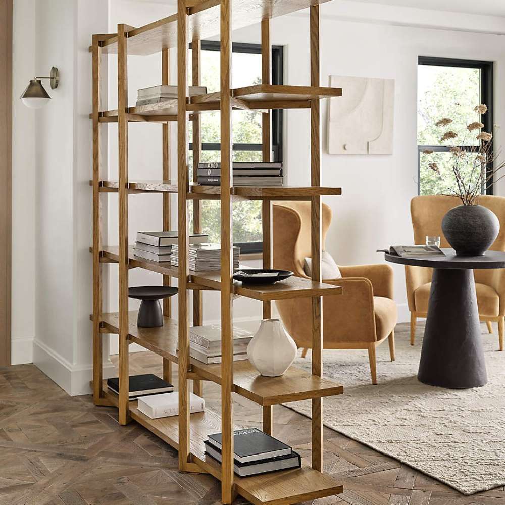 Crate & Barrel Thomas Barley Oak Wood Wide Open Bookcase/Room Divider styled as a room divider with books, vases, and decorative accents in a bright living space