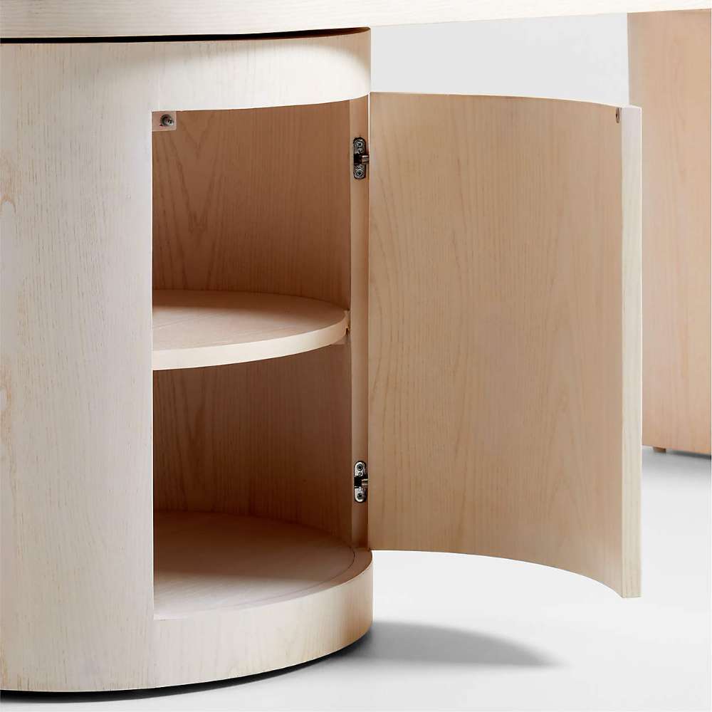 Crate & Barrel Twist 64" Whitewashed Ash Rotating Large Desk with Storage featuring an open storage cabinet with curved shelves inside the round base