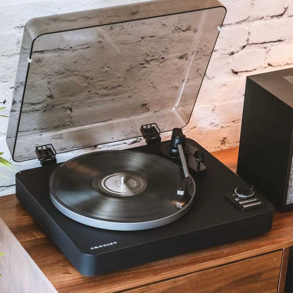 Crosley C300 Fully Automatic Turntable - Black is shown spinning a vinyl record with a sleek black design and a transparent dust cover